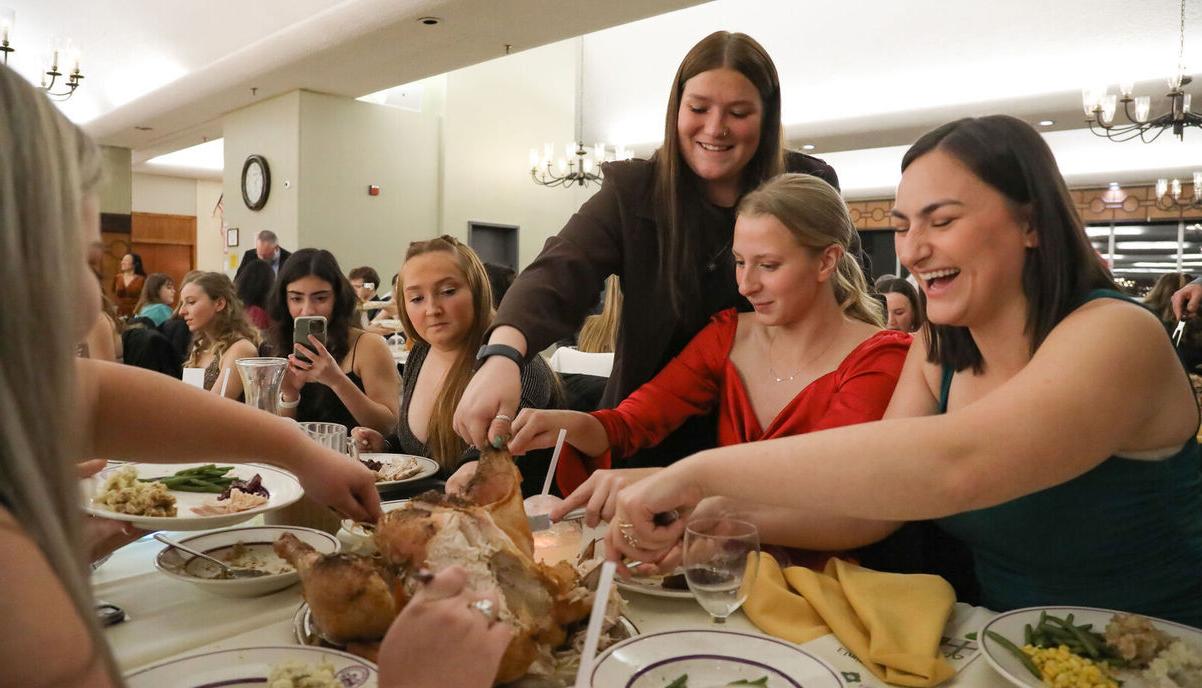 Students share some laughs as they cut into a turkey during the 节日宴会