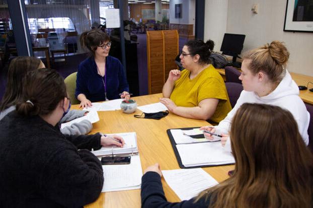 A professor works with a group of students in the Writing Center