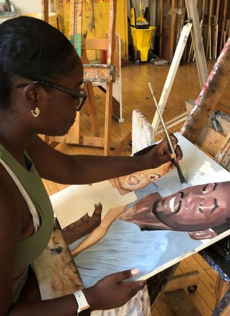 A student works on a painting of a man and child